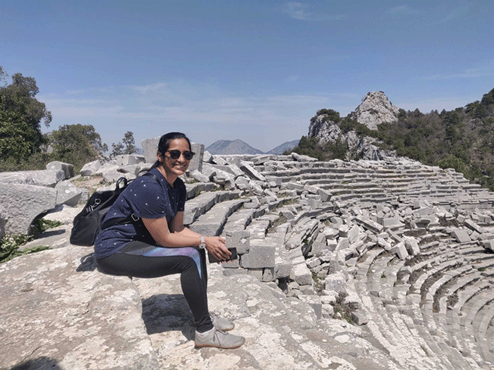 Vasavi sits in the sun at an ancient ampitheatre
