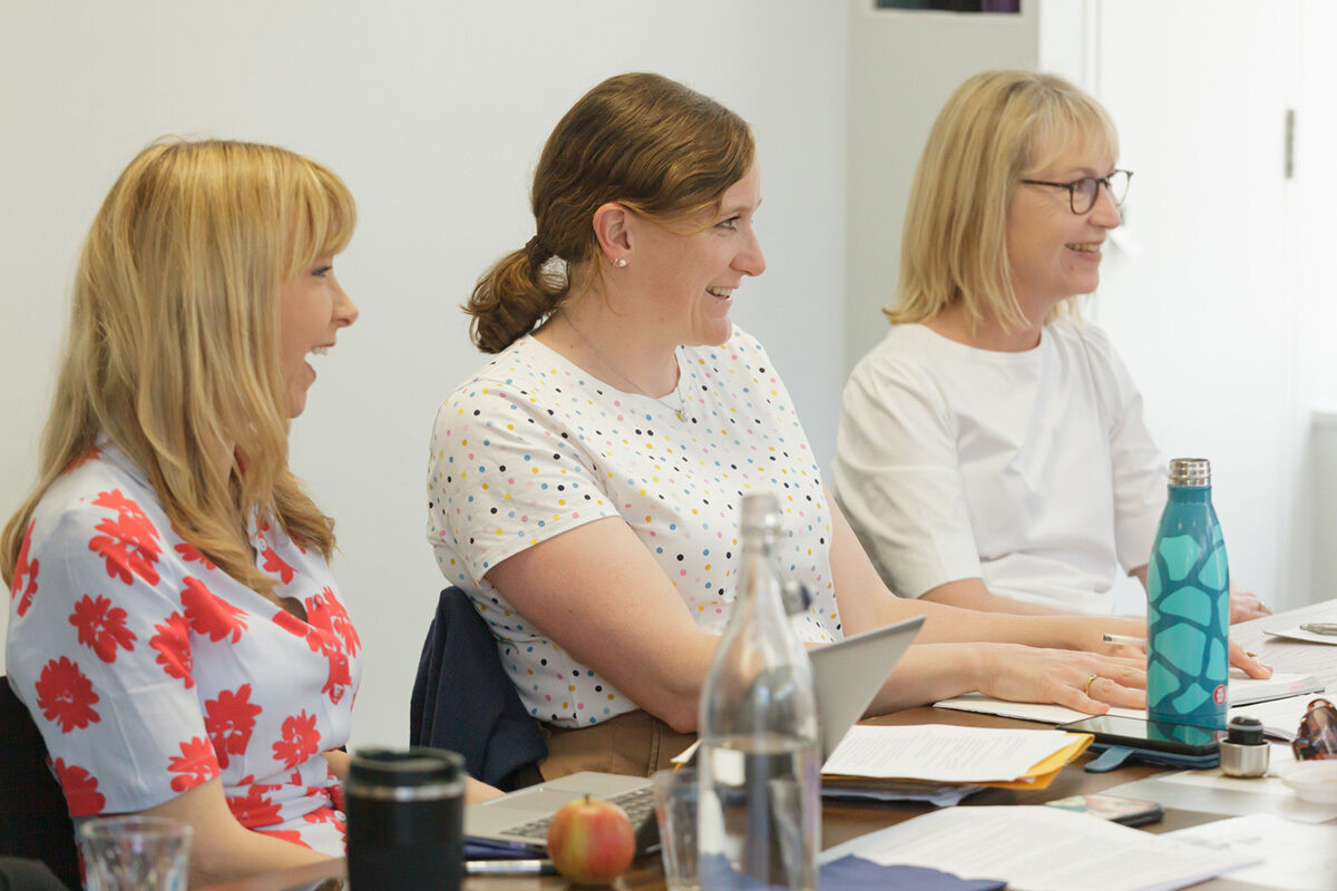 Three Participant Panel members listening and laughing in a meeting.